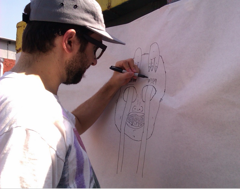 Daniel Harris drawing on sketch paper that has been wrapped around a dumpster